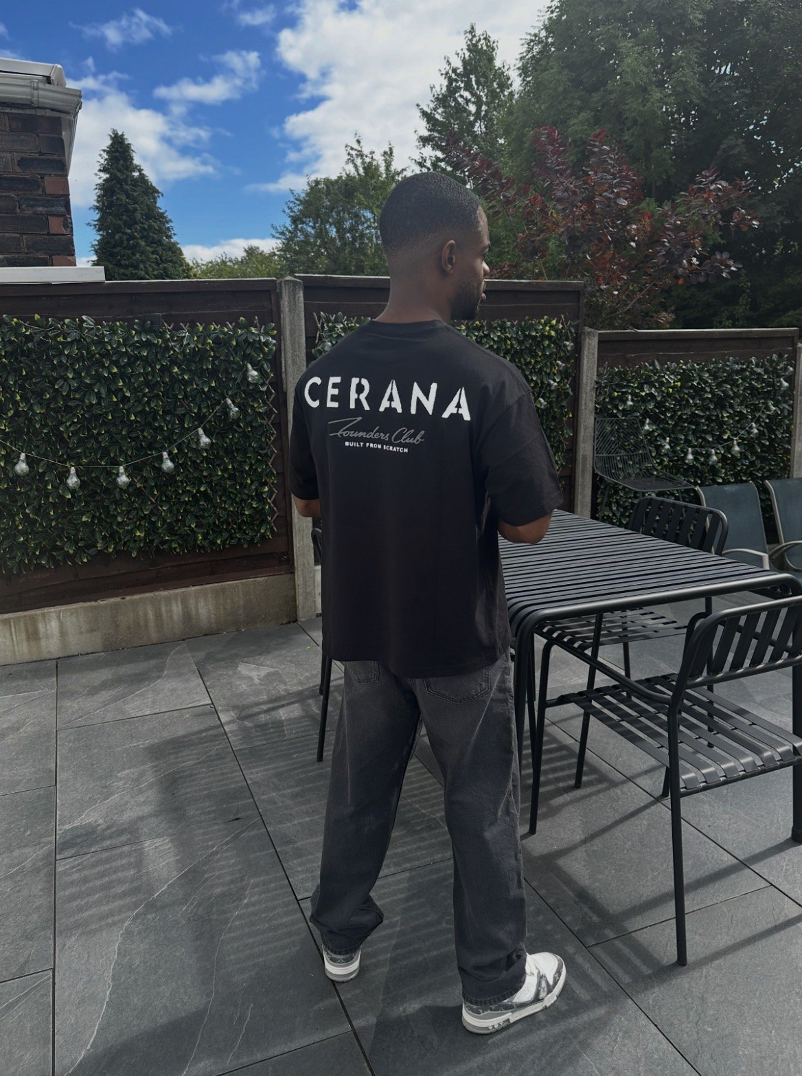 Cerana founder in a black tee, chest print, standing in a doorway.